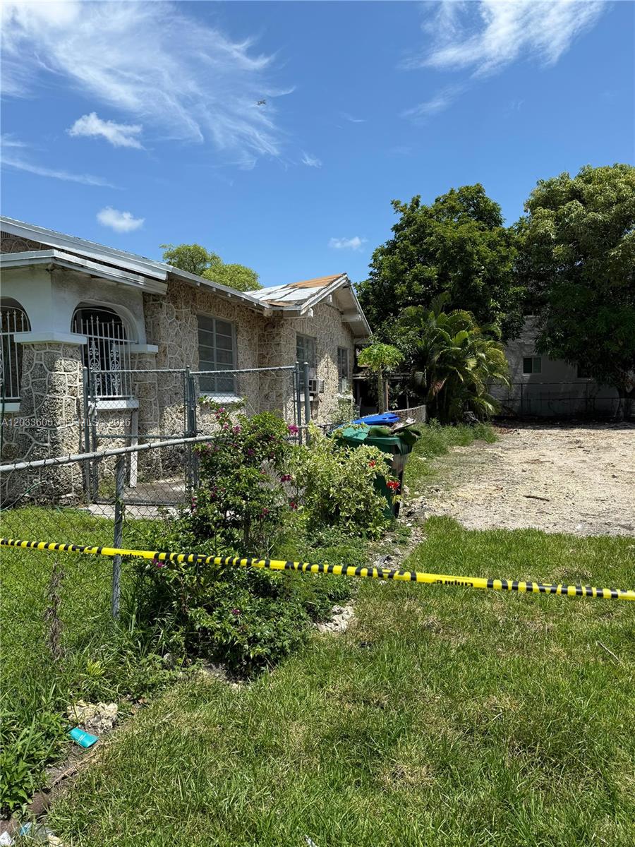 A stone-clad house with a damaged roof is partially enclosed by a chain-link fence — 1269 NW 4th St, Miami FL 33125, MIAMI, FL