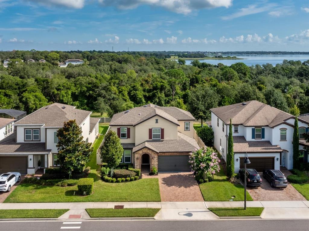 An aerial view of three suburban houses with driveways and lawns near a lake — 16971 TRADEWIND POINT, WINTER GARDEN, FL