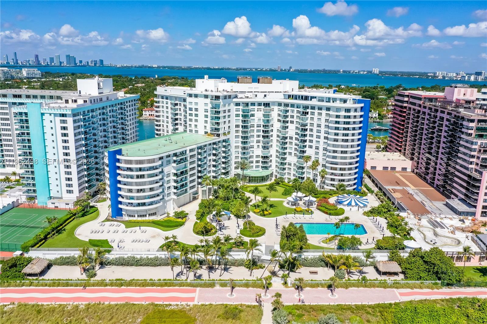 An aerial view of a large residential complex with a pool, gardens, and beach access — 5161 COLLINS AV # 1004, Miami Beach FL 33140, MIAMI BEACH, FL