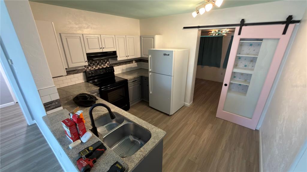 A kitchen features white cabinets, a black stove, a refrigerator, and a pink sliding door — 856 BERKSHIRE ROAD, DAYTONA BEACH, FL