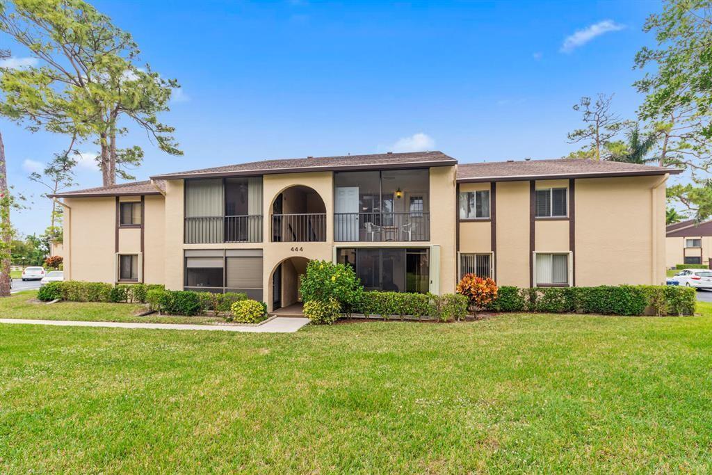 A two-story apartment building with beige stucco walls, dark trim, and screened-in balconies — 444 Pine Glen Lane # 1, FL 33463, FL