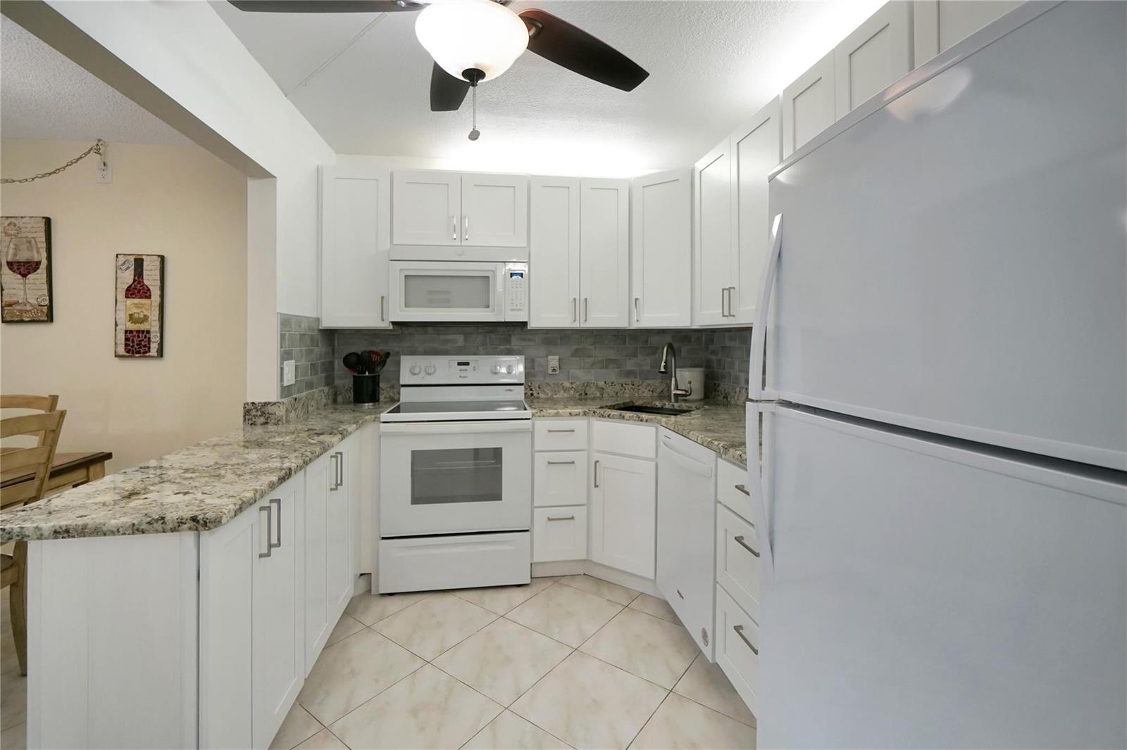 A kitchen with white cabinets, granite countertops, white appliances, and a tiled floor — 444 Pine Glen Lane # 1, FL 33463, FL
