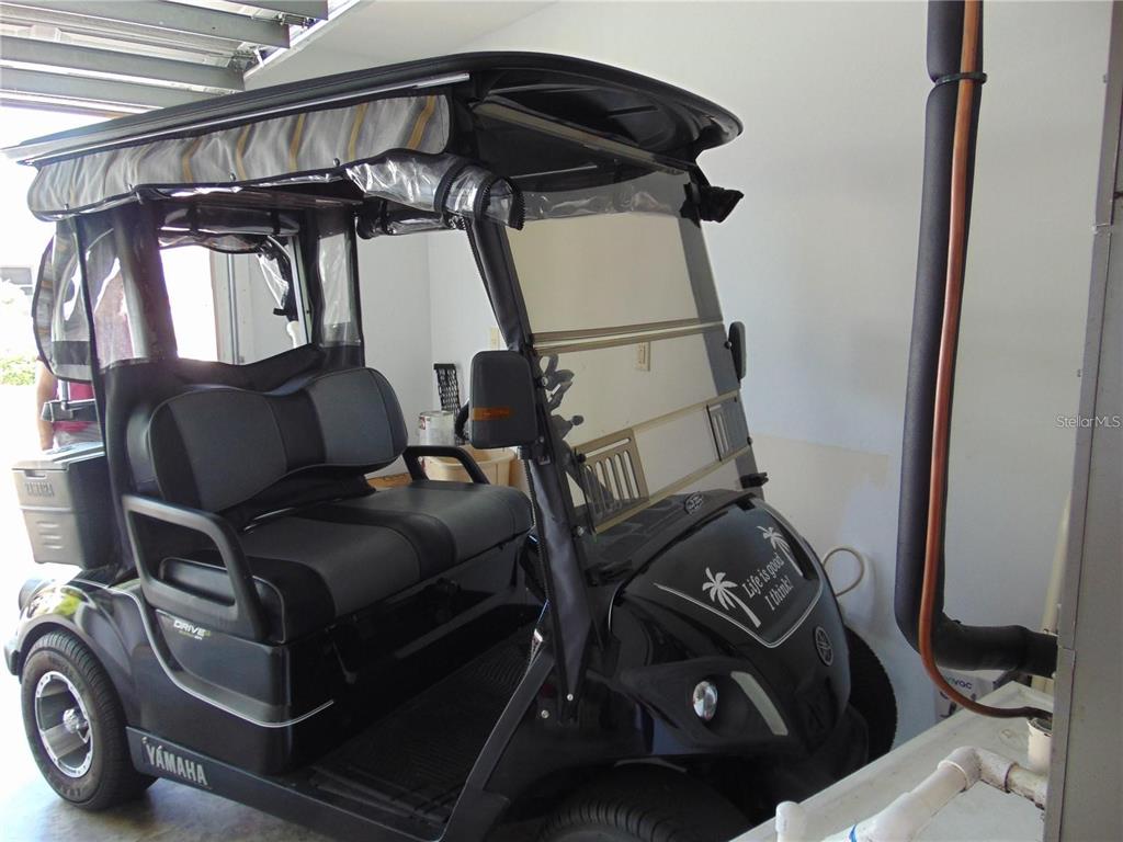 A black Yamaha golf cart with a roof and enclosure is parked inside a garage — 1420 FAIRWAY STREET, THE VILLAGES, FL