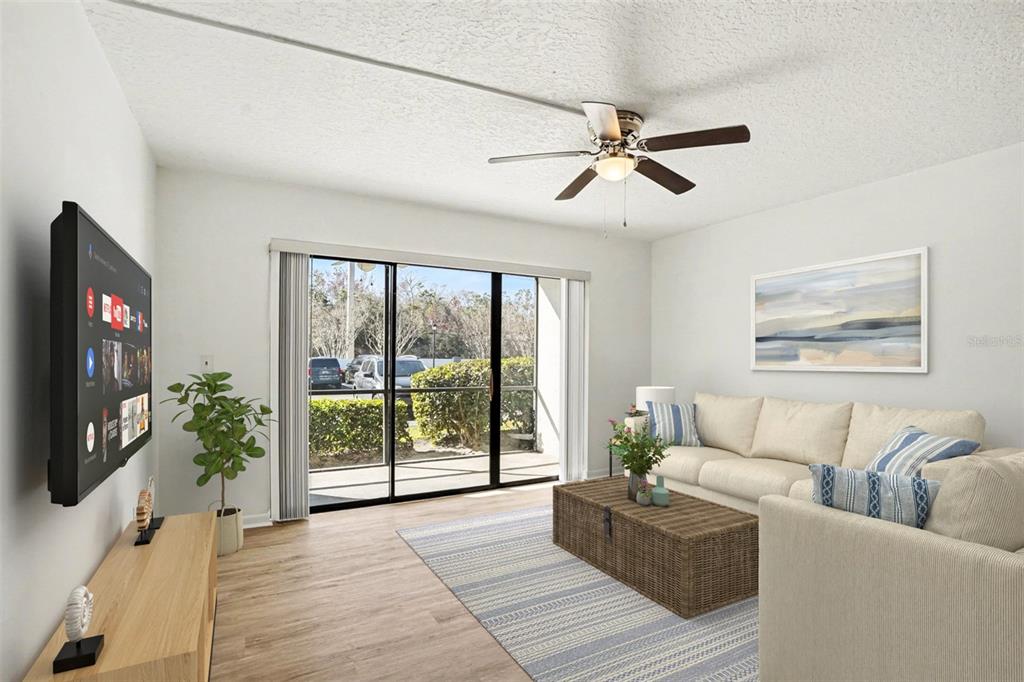 A living room features a beige sofa, a woven coffee table, and a sliding glass door — 1013 S PINE RIDGE CIRCLE UNIT 3C, SANFORD, FL