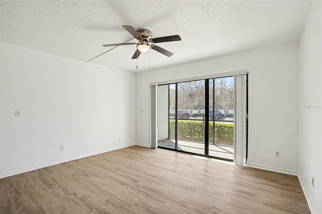 An empty room with white walls, wood-look flooring, a ceiling fan, and sliding glass doors — 1013 S PINE RIDGE CIRCLE UNIT 3C, SANFORD, FL