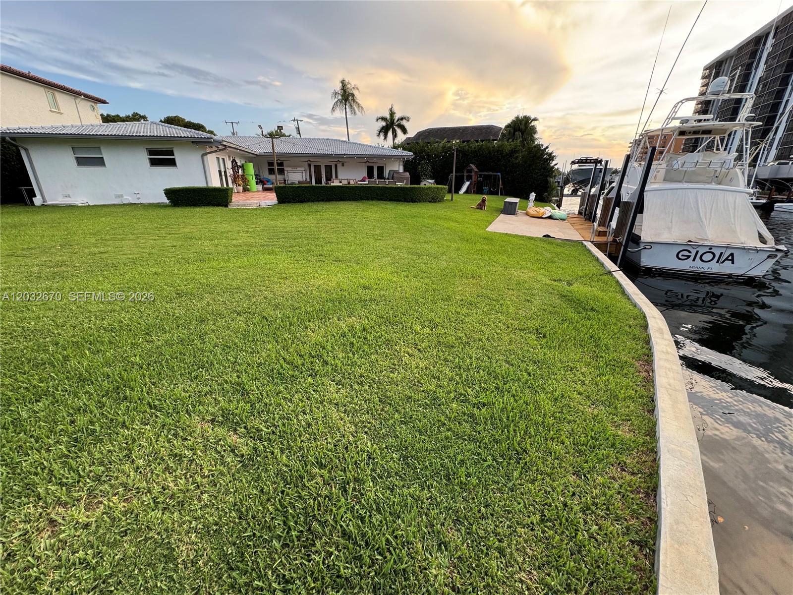 An aerial view shows a waterfront house with a pool, lawn, and multiple docked boats — 13305 Biscayne Island Ter, North Miami FL 33181, NORTH MIAMI, FL