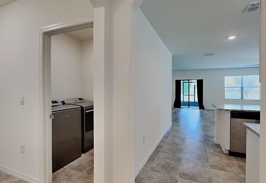A laundry room with stainless steel appliances is visible next to a tiled kitchen area — 3641 PEONY COURT SE, PALM BAY, FL