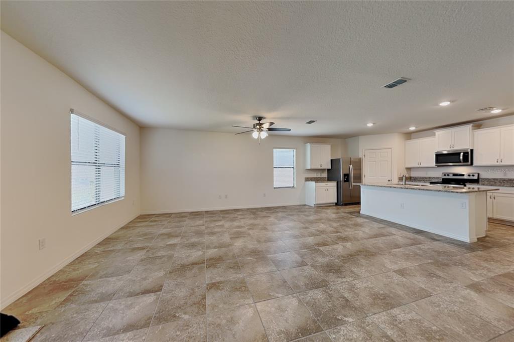 An open-concept kitchen and living area features tile flooring, white cabinetry, and a center island — 3641 PEONY COURT SE, PALM BAY, FL