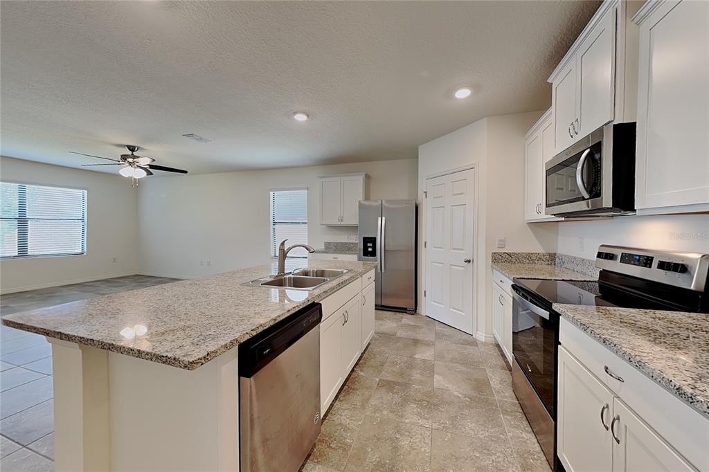 A kitchen with white cabinets, granite countertops, stainless steel appliances, and an island — 3641 PEONY COURT SE, PALM BAY, FL