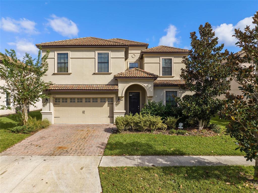 A two-story stucco house features a tiled roof, a two-car garage, and a front entrance — 1453 BELLE TERRE ROAD, DAVENPORT, FL