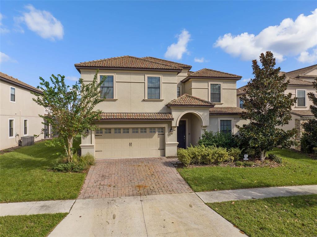 A two-story suburban house with a beige stucco exterior, tiled roof, and a paved driveway — 1453 BELLE TERRE ROAD, DAVENPORT, FL
