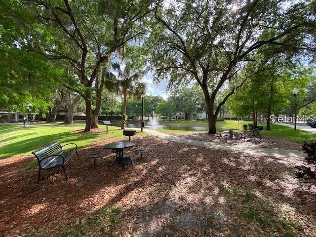 A park area features a bench, a picnic table, and a fountain in the background — 2900 EDENSHIRE WAY UNIT 107, KISSIMMEE, FL