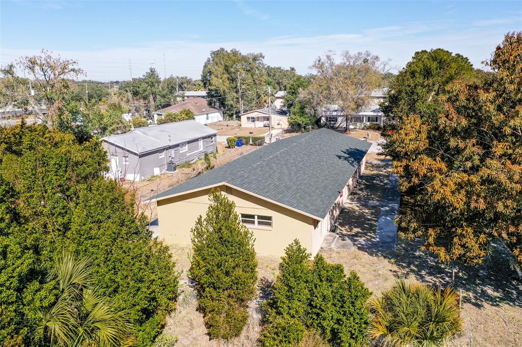 An aerial view shows a tan building with a dark shingled roof and surrounding trees — 140 AVENUE W NW UNIT 3, WINTER HAVEN, FL