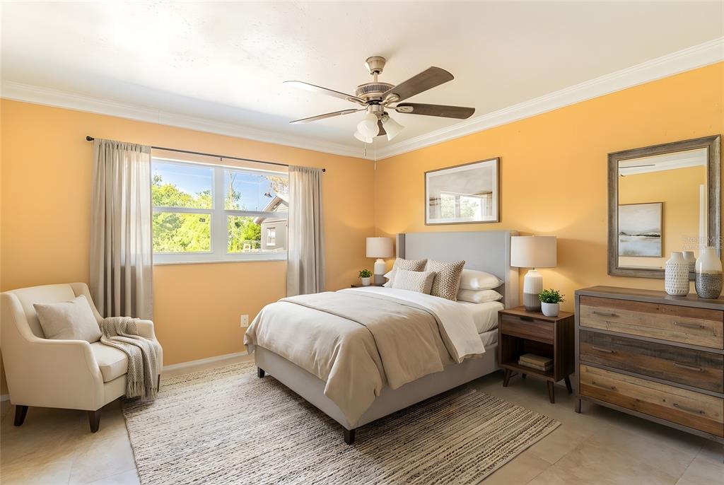A bedroom features orange walls, a gray upholstered bed, a ceiling fan, and a dresser — 140 AVENUE W NW UNIT 3, WINTER HAVEN, FL