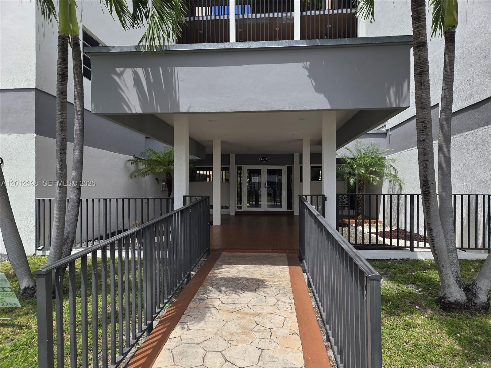 A stone walkway leads to the entrance of a building with a covered porch — 4670 W 13th Ln # 507, Hialeah FL 33012, HIALEAH, FL