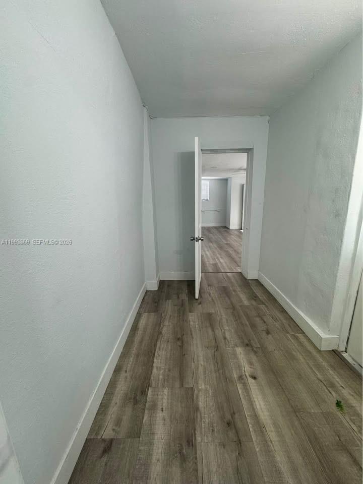 A narrow hallway with light gray walls and wood-look flooring leads to an open room — 7620 SW 21 # 2, Miami FL 33155, MIAMI, FL