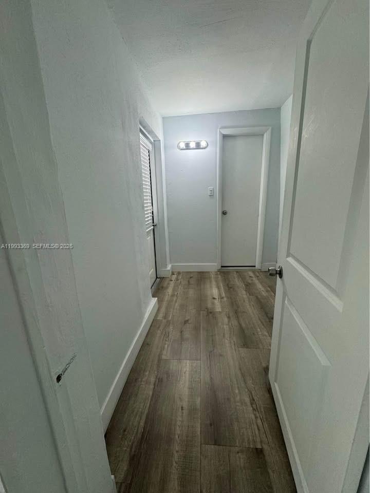 A narrow hallway features light-colored walls, wood-look flooring, and two closed doors — 7620 SW 21 # 2, Miami FL 33155, MIAMI, FL
