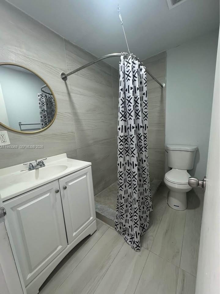 A bathroom features a white vanity, a round mirror, a toilet, and a walk-in shower — 7620 SW 21 # 2, Miami FL 33155, MIAMI, FL