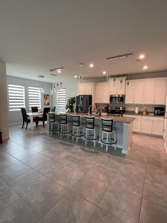 A kitchen with white cabinets, granite countertops, and a breakfast bar with four stools — 1100 LONE PALM WAY, ST CLOUD, FL