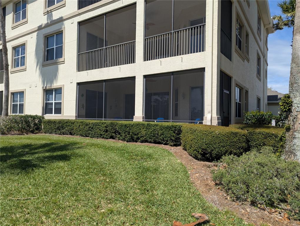 A multi-story apartment building features screened-in balconies and manicured hedges on a sunny day — 200 RIVERFRONT DRIVE UNIT D101, PALM COAST, FL