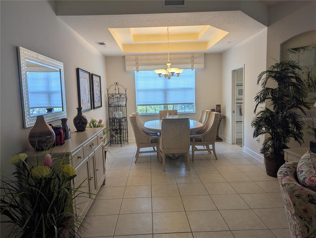 A dining room features a tray ceiling, tile flooring, a round table, and a sideboard — 200 RIVERFRONT DRIVE UNIT D101, PALM COAST, FL
