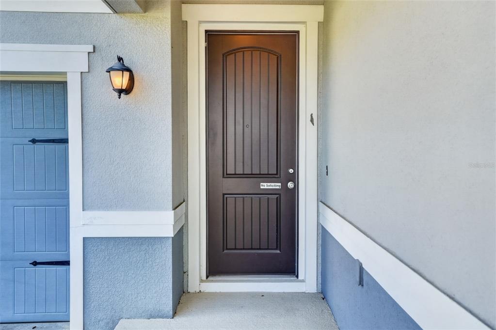 A brown front door with a no soliciting sign sits beside a blue garage door — 2364 CARRIAGE POINTE LOOP, APOPKA, FL