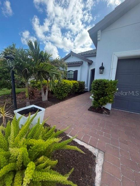 A paved walkway leads to the entrance of a house with a gray garage door — 6289 MESA GLEN, BRADENTON, FL