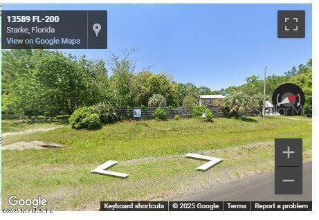 A grassy lot with a wooden fence and trees viewed from a roadside — 13620 US HIGHWAY 301 S, STARKE, FL
