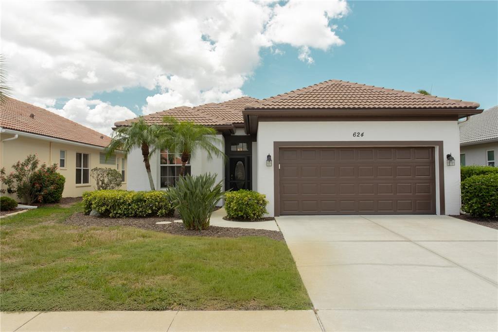 A single-story house with a brown tile roof, white stucco walls, and a two-car garage — 624 SILK OAK DRIVE, VENICE, FL