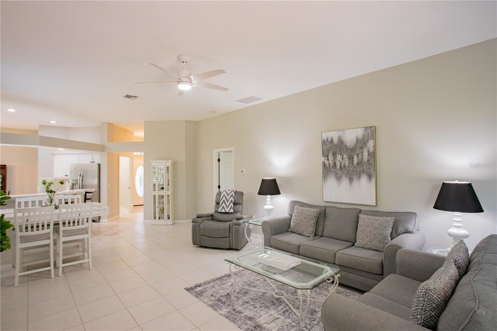 A living room with light tile floors, a grey sofa, and a ceiling fan — 624 SILK OAK DRIVE, VENICE, FL