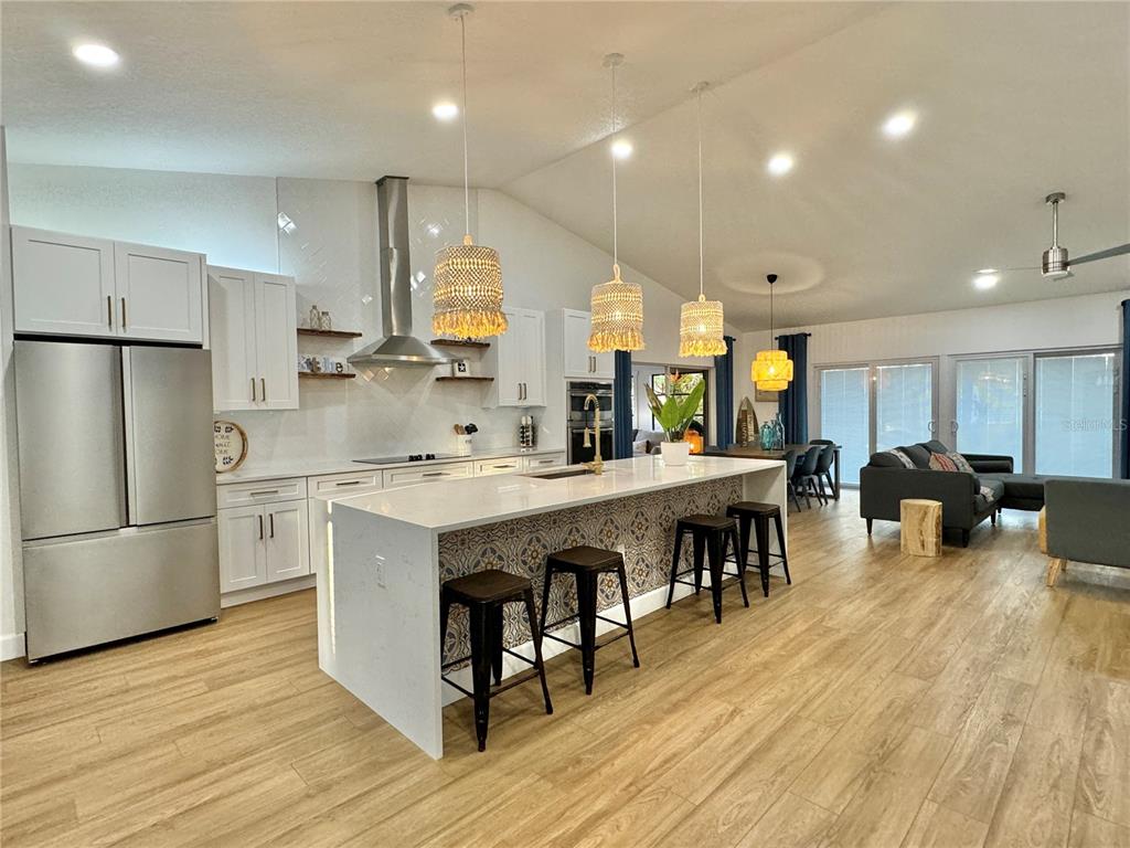 A modern kitchen features white cabinetry, a patterned island, and pendant lighting in an open-concept space — 3409 45TH STREET W, BRADENTON, FL