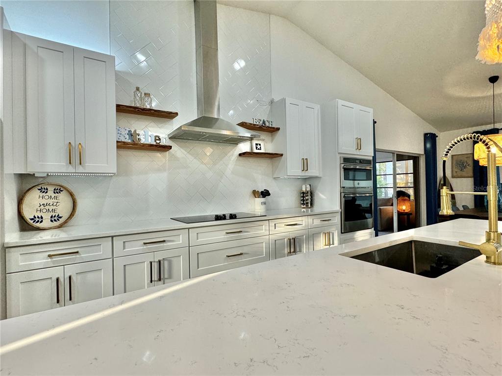 A modern kitchen features white cabinetry, a herringbone tile backsplash, and a large quartz island — 3409 45TH STREET W, BRADENTON, FL