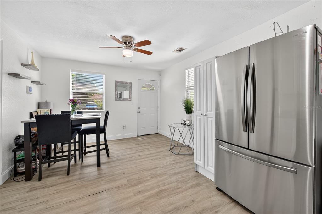 A dining area features a stainless steel refrigerator, a table with chairs, and wood flooring — 1318 SAN JOSE BOULEVARD, DAYTONA BEACH, FL