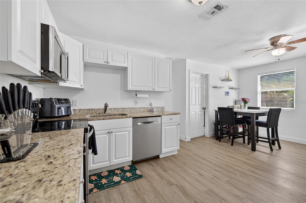 A kitchen with white cabinets, granite countertops, stainless steel appliances, and an adjacent dining area — 1318 SAN JOSE BOULEVARD, DAYTONA BEACH, FL