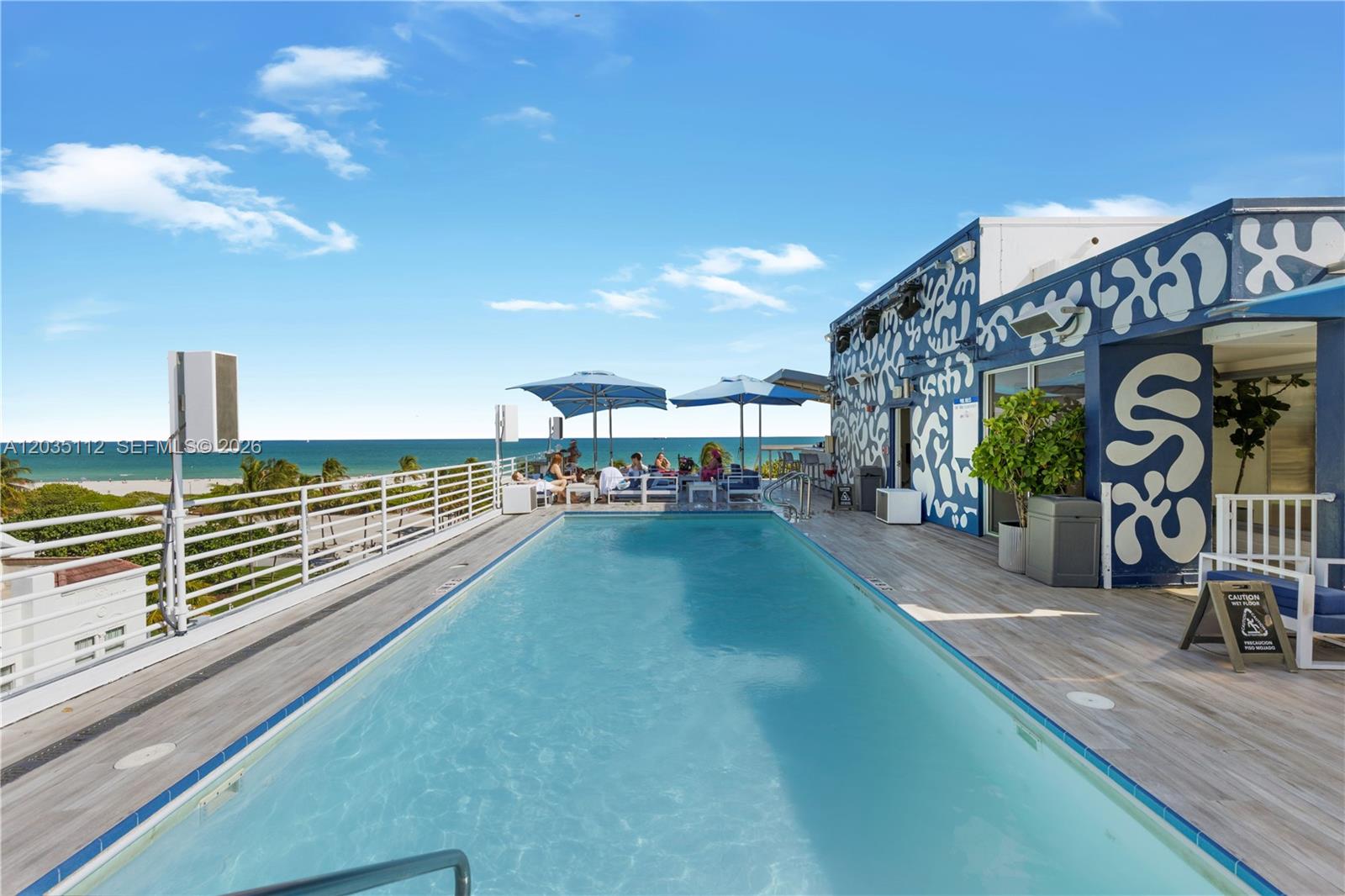 A rooftop swimming pool overlooks the ocean with lounge chairs and a patterned building exterior — 1024 Ocean Dr # A402, Miami Beach FL 33139, MIAMI BEACH, FL