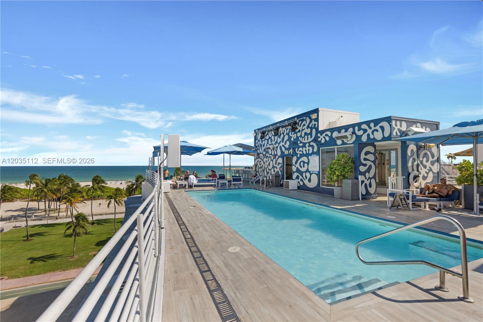 A rooftop swimming pool overlooks a beach with palm trees and a blue sky — 1024 Ocean Dr # A402, Miami Beach FL 33139, MIAMI BEACH, FL