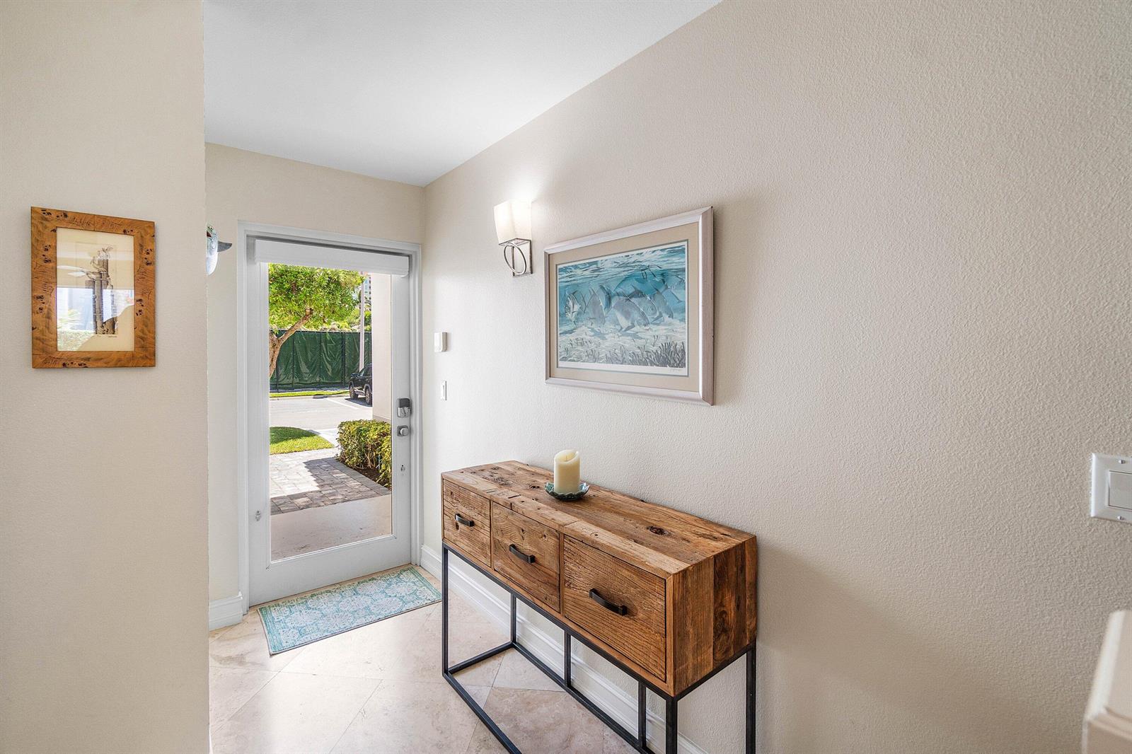 An entryway features a wooden console table, two framed wall pictures, and an open door — 3604 S Ocean Boulevard # 105, Highland Beach FL 33487, HIGHLAND BEACH, FL