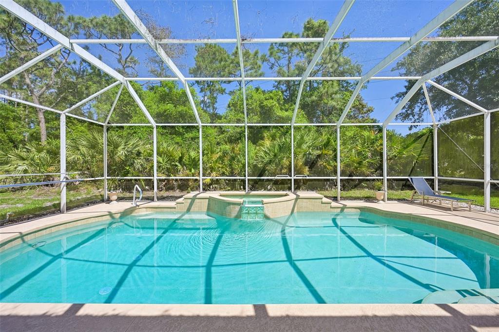 A swimming pool with an integrated spa is enclosed by a screened lanai — 546 SEVILLA DRIVE, ST AUGUSTINE, FL