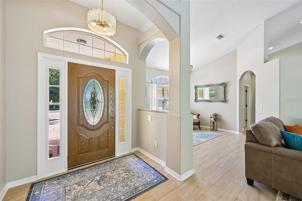 An entryway with a wood front door, arched architectural details, and light-colored tile flooring — 546 SEVILLA DRIVE, ST AUGUSTINE, FL