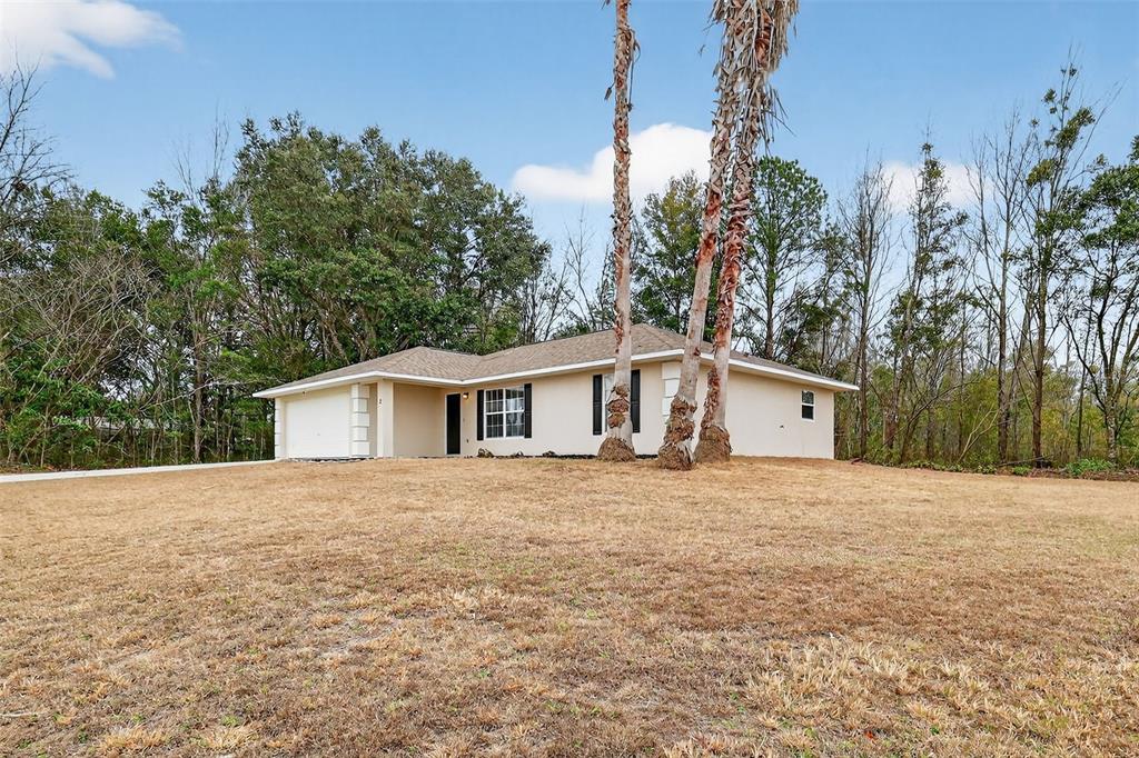 A single-story house with a beige exterior and a garage sits on a grassy lot — 2 PINE TRACK TERRACE, OCALA, FL