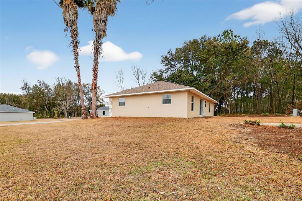 A beige house with a hip roof sits on a large, dry grassy lot — 2 PINE TRACK TERRACE, OCALA, FL