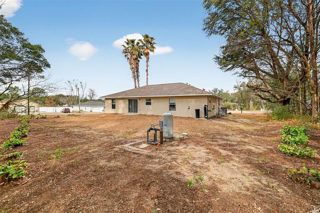 The exterior of a beige house features a large yard with a well pump — 2 PINE TRACK TERRACE, OCALA, FL