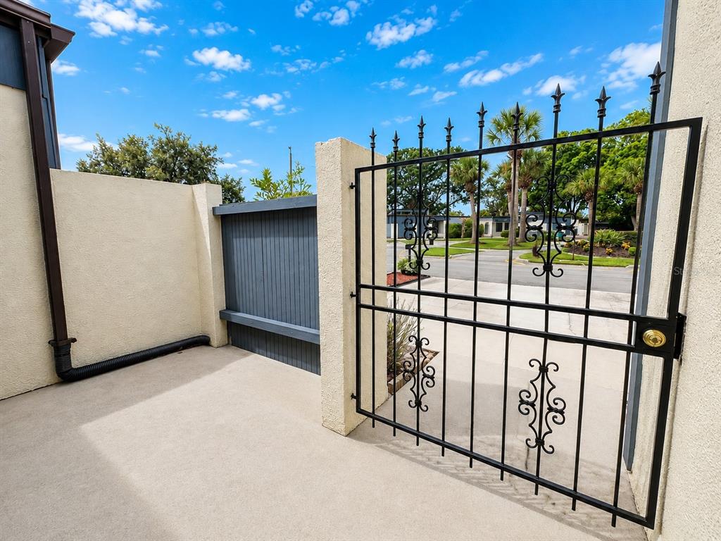 A concrete patio features a black metal gate and a gray wooden privacy fence — 2653 CAYMAN WAY, WINTER PARK, FL