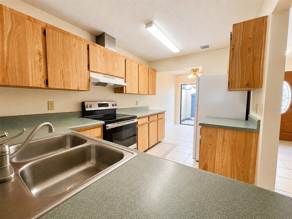 A kitchen features light wood cabinets, green laminate countertops, and a black electric range — 2653 CAYMAN WAY, WINTER PARK, FL