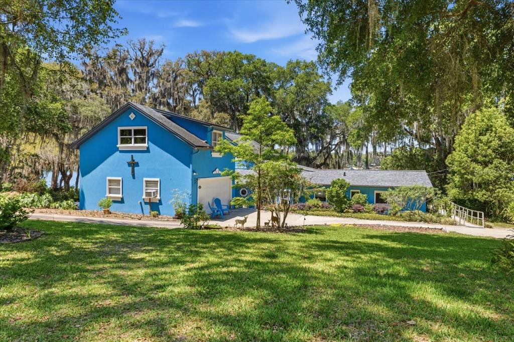 A bright blue two-story house with a garage sits on a grassy lot with trees — 8386 AUSTIN ROAD, MELROSE, FL