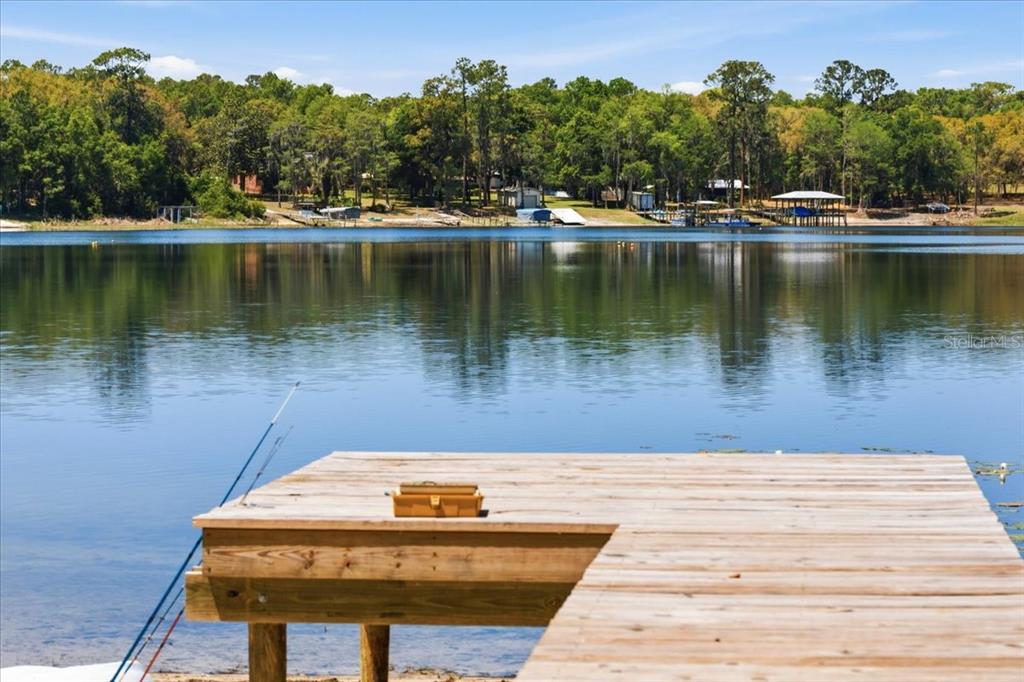 A wooden dock extends into a calm lake with a forested shoreline in the background — 8386 AUSTIN ROAD, MELROSE, FL