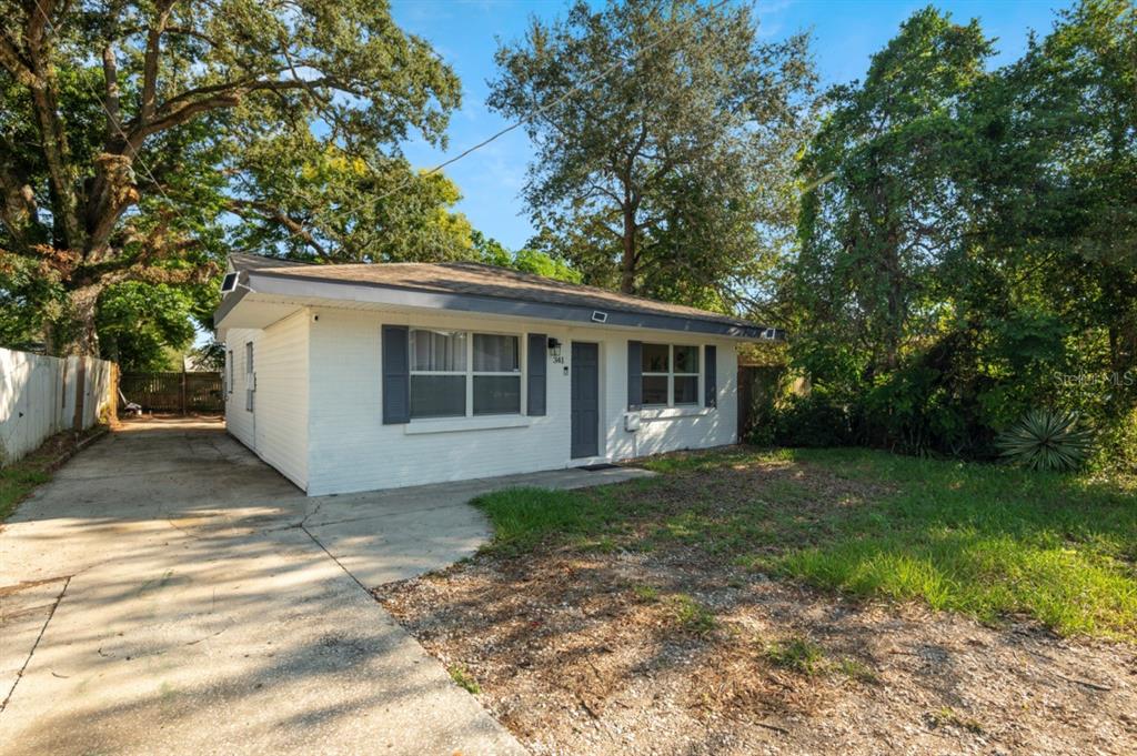 A white, single-story house with a gray roof and shutters sits next to a driveway — 341 AVENUE L NE, WINTER HAVEN, FL