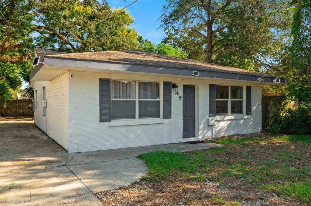 A single-story white brick house with a gray door, gray shutters, and a concrete driveway — 341 AVENUE L NE, WINTER HAVEN, FL