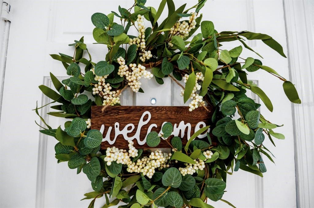 A decorative wreath with green leaves and white berries hangs on a white door — 341 AVENUE L NE, WINTER HAVEN, FL