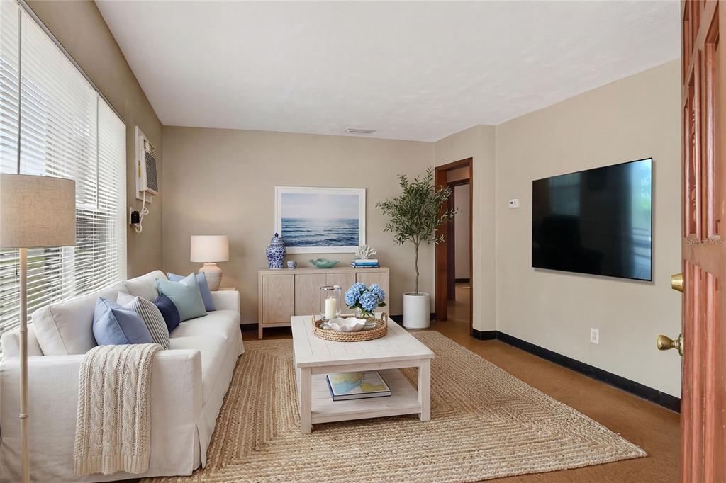 A living room features a white sofa, a coffee table, and a wall-mounted television — 1248 WOODLAND AVENUE, LAKELAND, FL